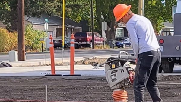 Construction worker operating a plate compactor on a job site in Idaho